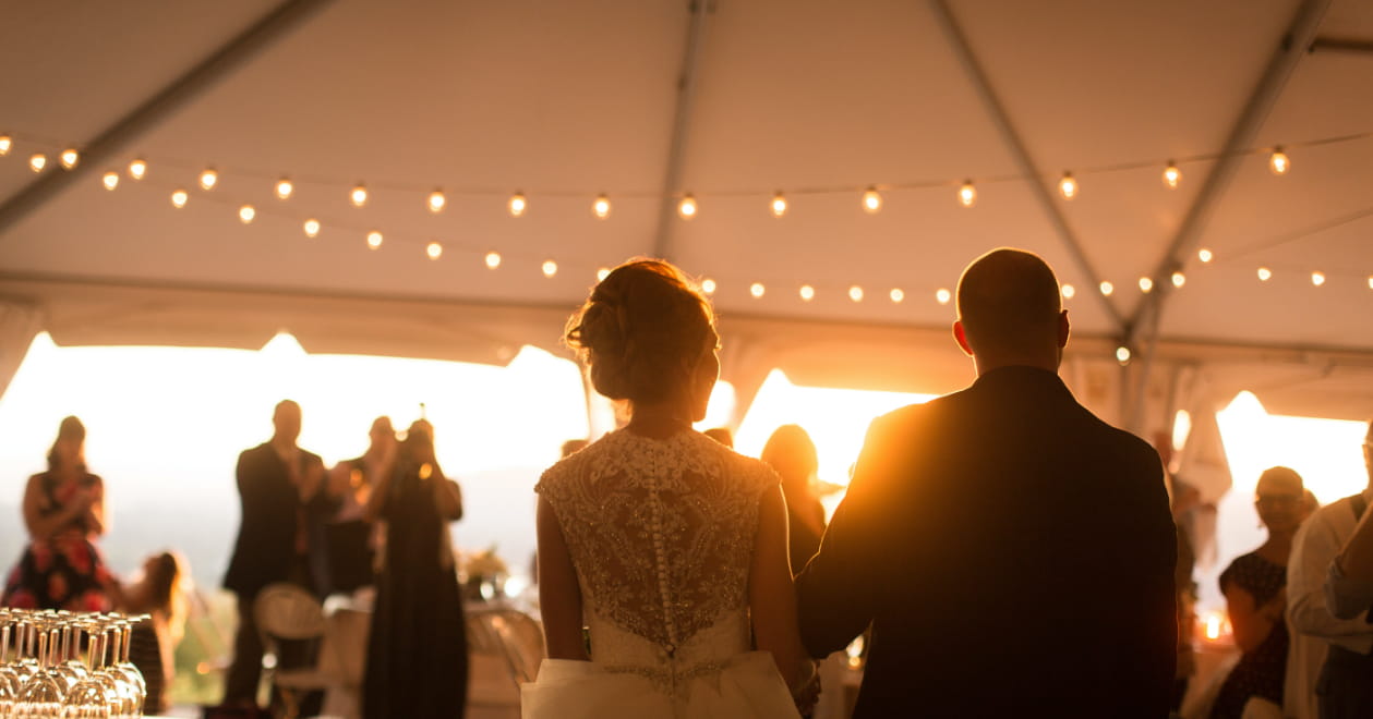 wedding couple holding hands on the dance floor with sun setting